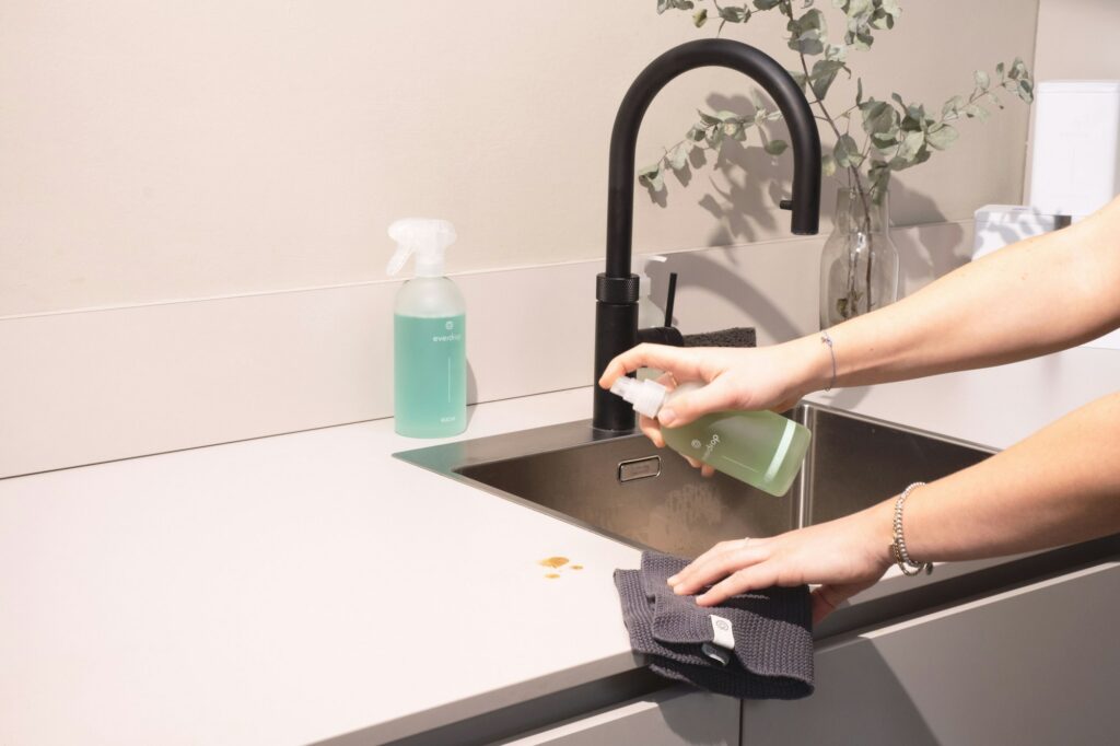 Huishoudhulp maakt een keukenaanrecht en spoelbak schoon